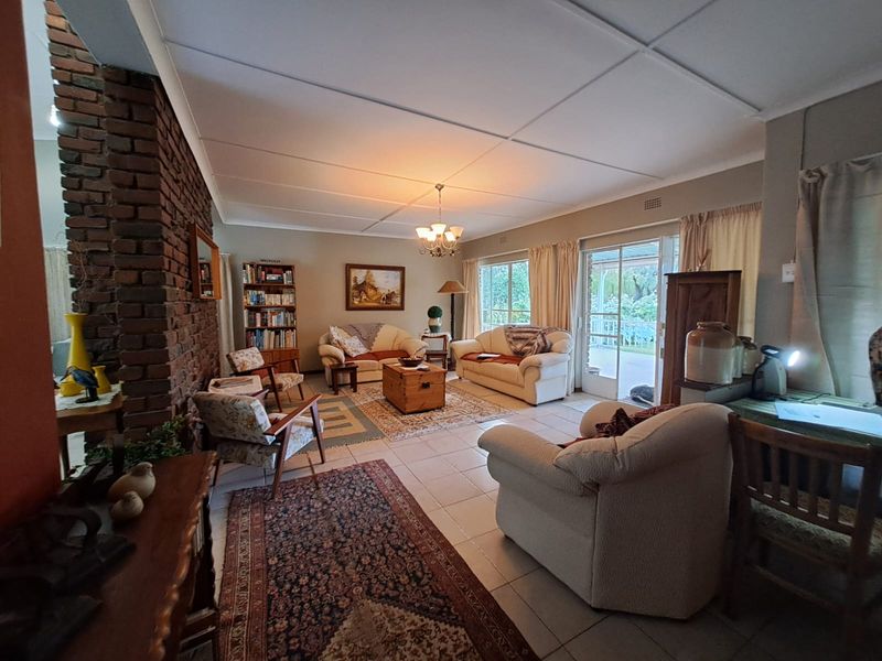 Spacious living room featuring an exposed brick fireplace, tiled flooring, and sliding glass doors providing natural light and access to the outdoor area.