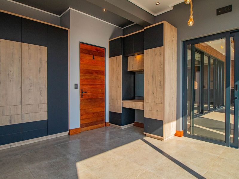 Modern bedroom featuring extensive built-in cabinetry, a dedicated vanity area, tiled flooring, and direct access to an outdoor patio through sliding glass doors.