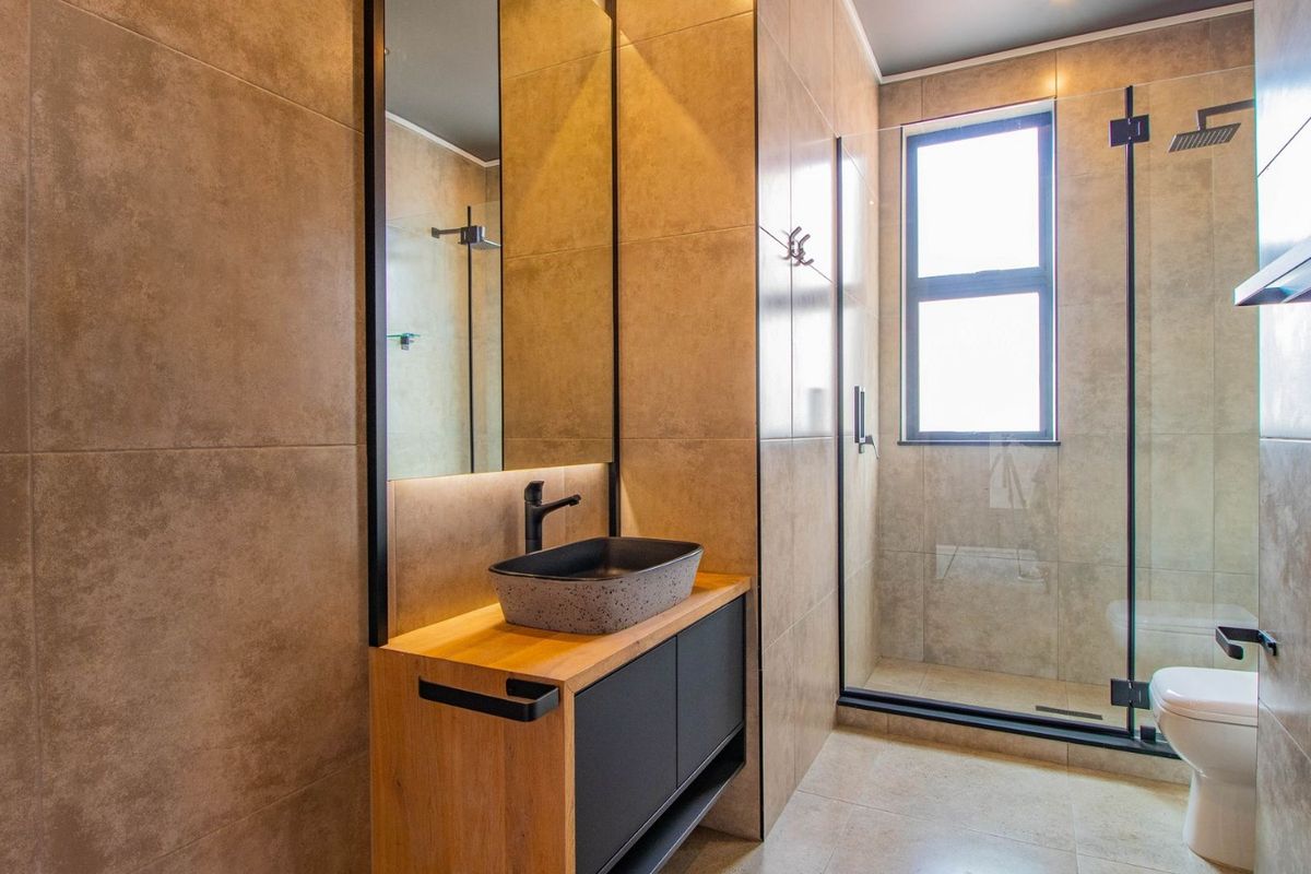 Modern bathroom featuring a vessel sink on a wooden vanity, a walk-in shower with a glass screen, and contemporary tiled finishes.
