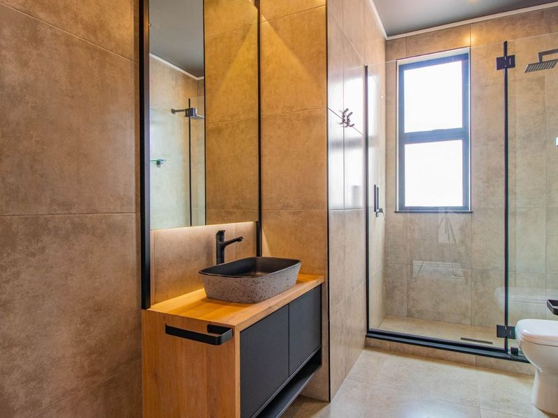 Modern bathroom featuring a vessel sink on a wooden vanity, a walk-in shower with a glass screen, and contemporary tiled finishes.
