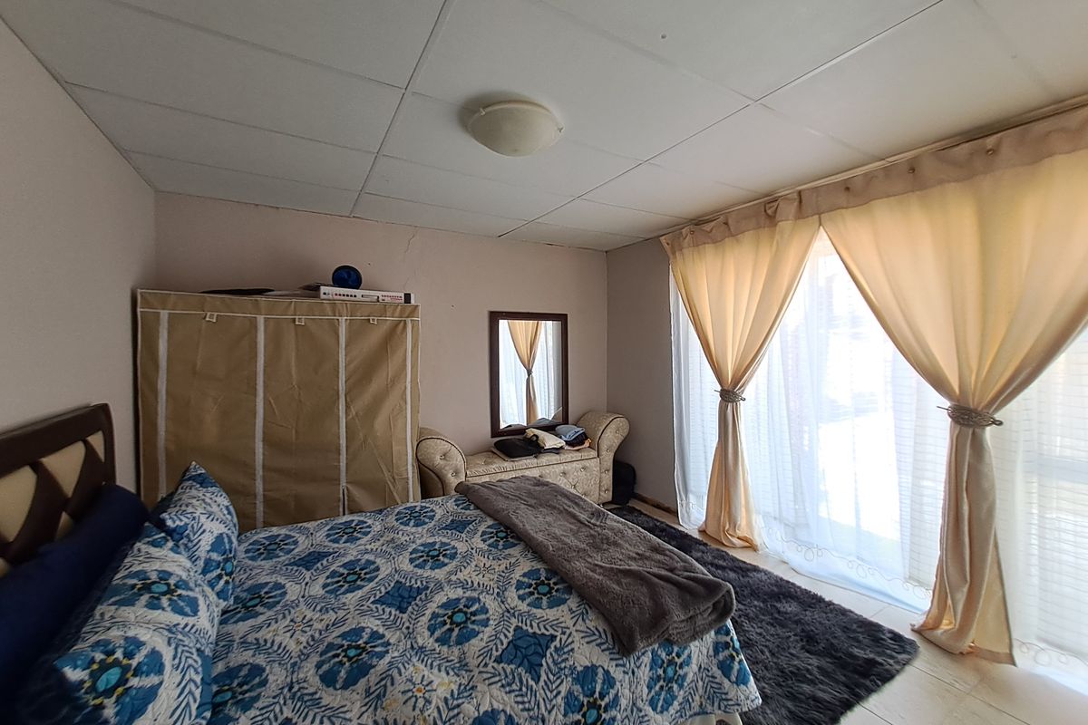 A bedroom featuring tiled flooring, a drop ceiling, and a sliding glass door providing natural light.