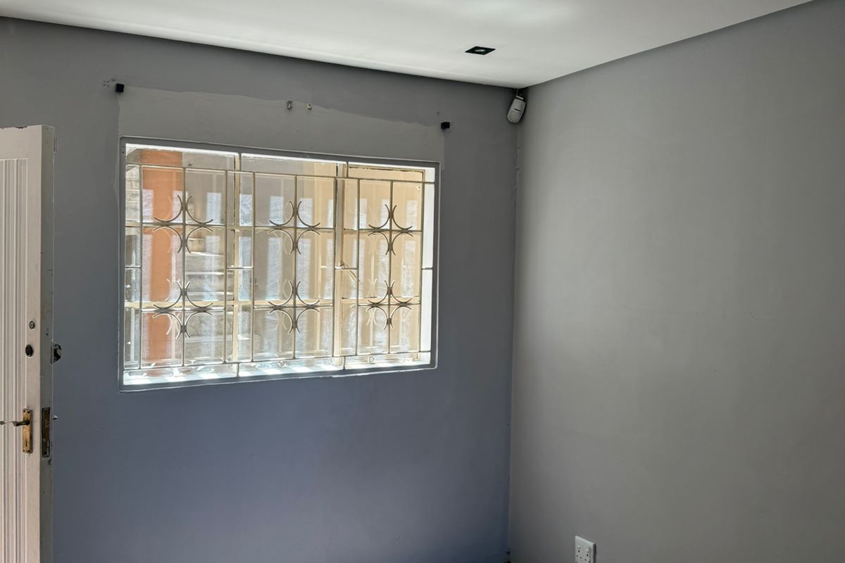 A vacant bedroom featuring tiled flooring, a window with security bars, and recessed ceiling lighting.