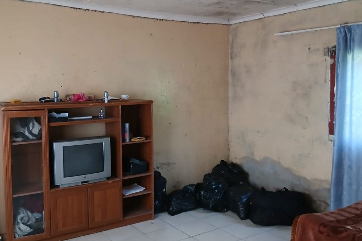 A bedroom space requiring significant renovation, featuring tiled floors and visible wall and ceiling damage throughout the room.