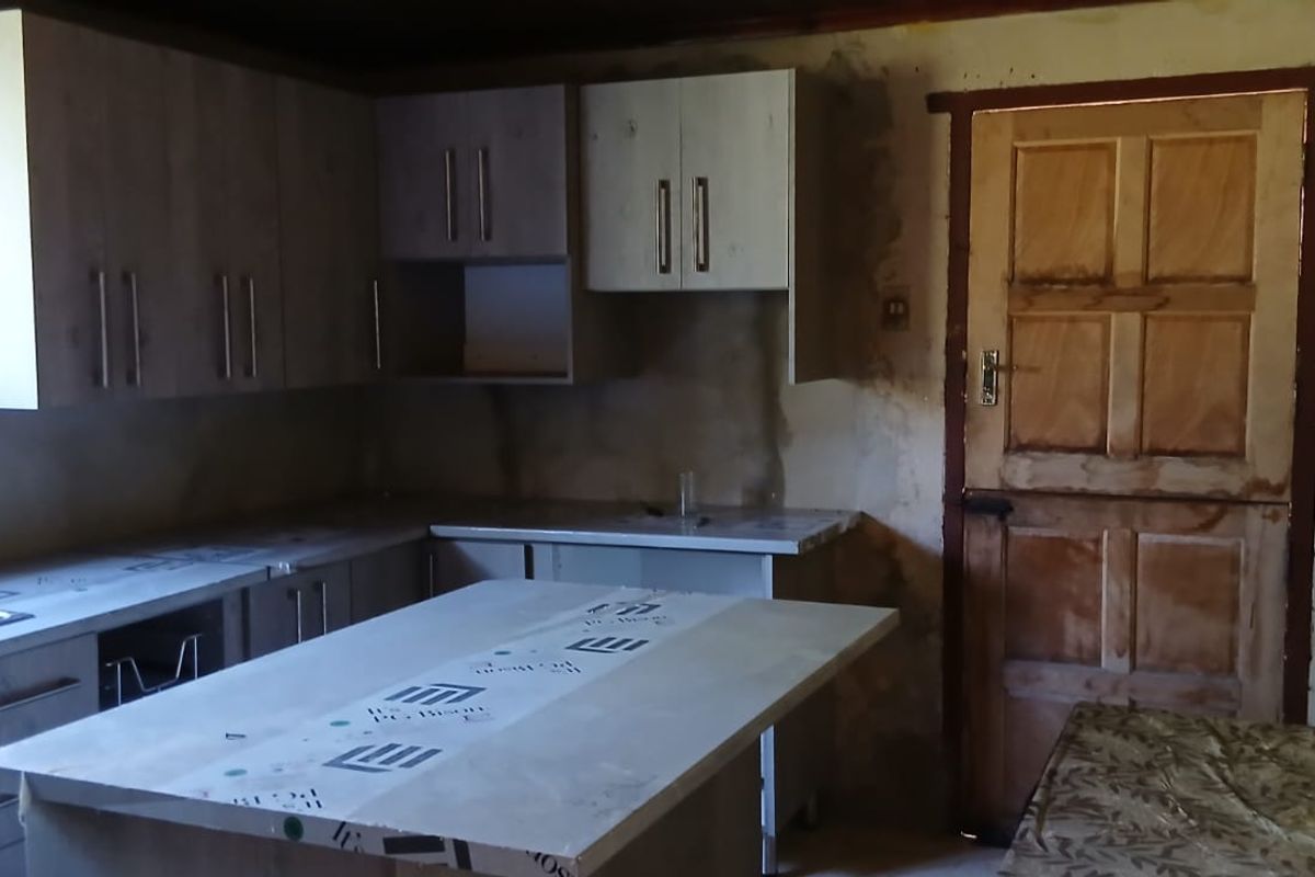 An unfinished kitchen space featuring new cabinetry and countertops, requiring wall finishing and final installation to complete the renovation.