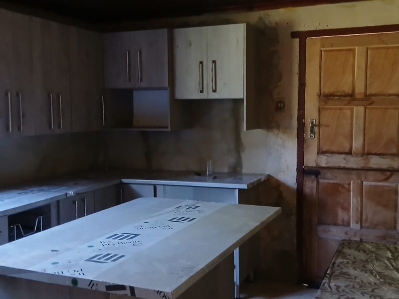 An unfinished kitchen space featuring new cabinetry and countertops, requiring wall finishing and final installation to complete the renovation.