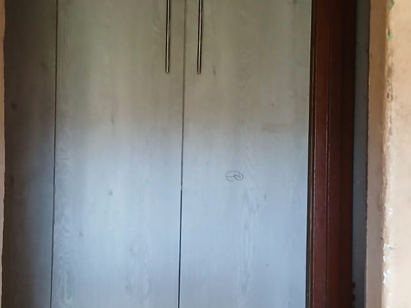 A narrow hallway featuring a built-in cupboard with light wood-grain finish and tiled flooring, requiring minor cosmetic repairs to walls and trim.