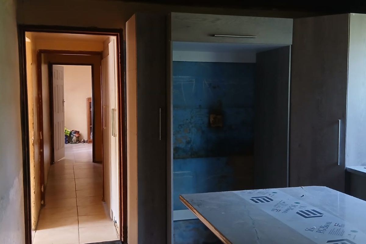 An unfinished kitchen area featuring built-in cabinetry, a double bowl sink, and visible wall repair requirements, offering potential for custom renovation.