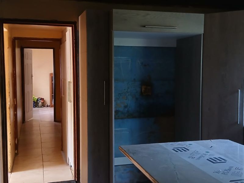 An unfinished kitchen area featuring built-in cabinetry, a double bowl sink, and visible wall repair requirements, offering potential for custom renovation.