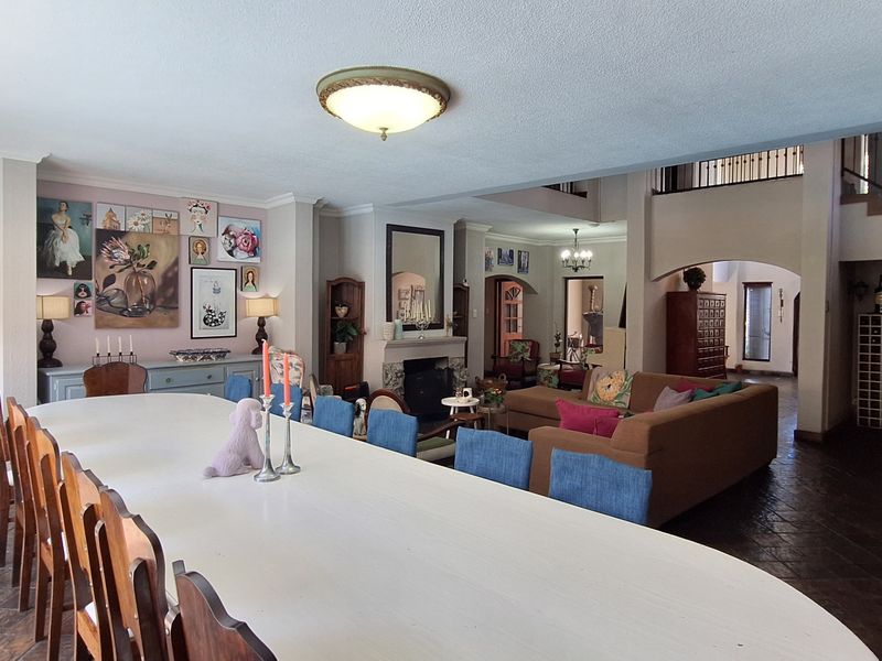 Spacious open-plan living and dining area featuring slate tile flooring, a central fireplace, and a staircase with a wrought iron balustrade.