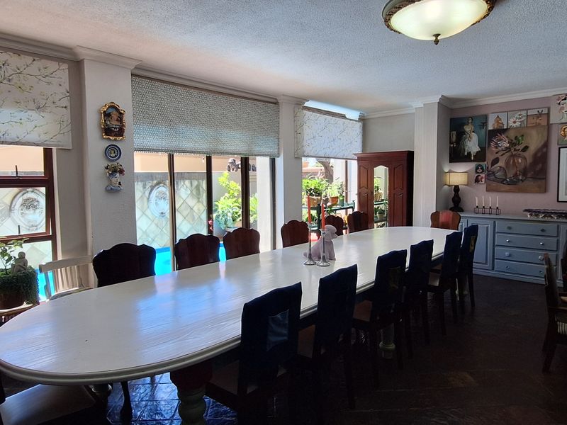 Spacious dining room featuring tiled flooring, large sliding glass doors providing natural light, and direct views of the outdoor pool area.