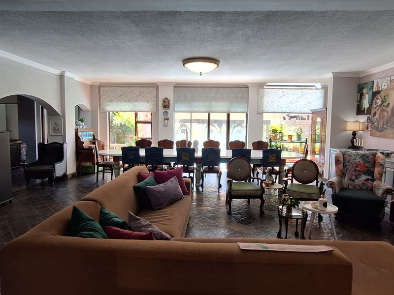 Spacious open-plan living and dining area featuring terracotta tile flooring, a fireplace, and large sliding glass doors leading to the outdoor space.