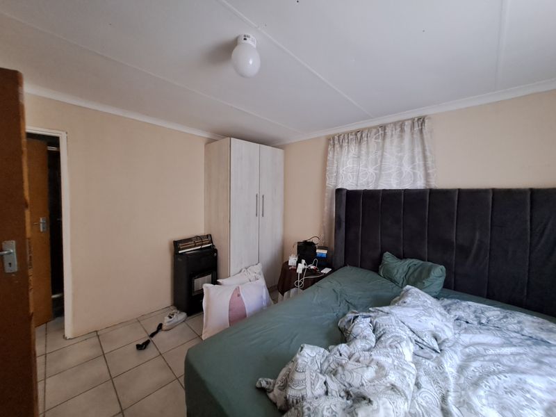 A functional bedroom featuring tiled flooring, a built-in wardrobe, and a coved ceiling, providing a neutral base for personalization.