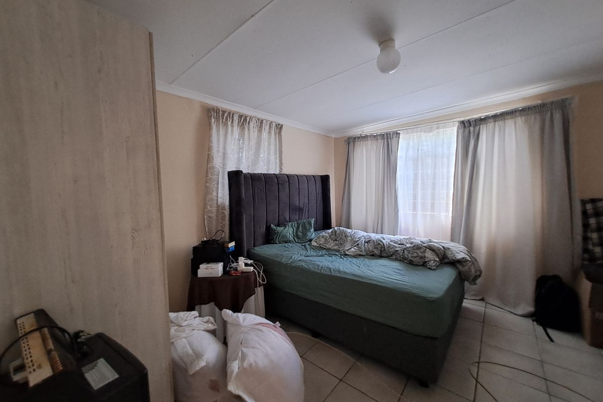 A functional bedroom featuring tiled flooring and a built-in cupboard, offering a neutral base for potential interior updates.