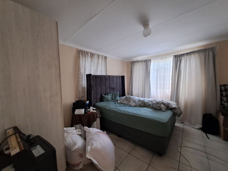 A functional bedroom featuring tiled flooring and a built-in cupboard, offering a neutral base for potential interior updates.