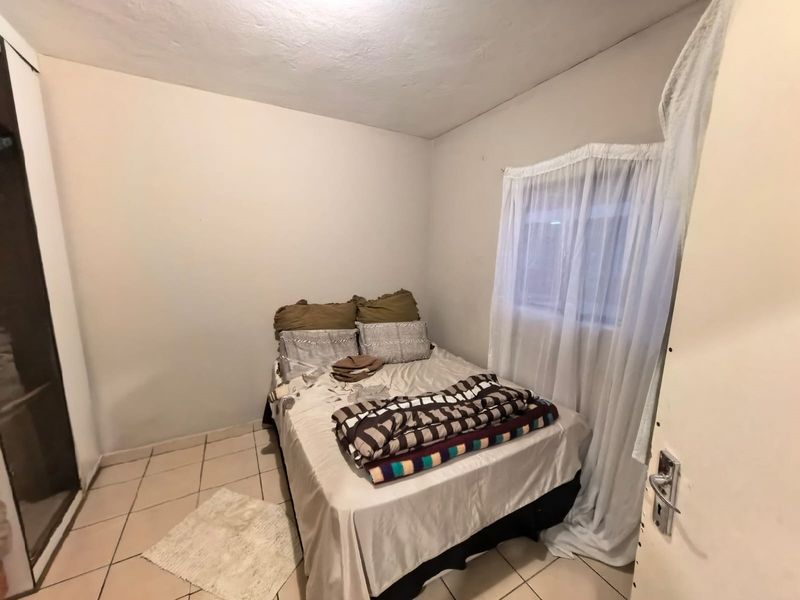 A compact bedroom featuring tiled flooring and a built-in wardrobe, offering a functional space ready for cosmetic updates and modernization.