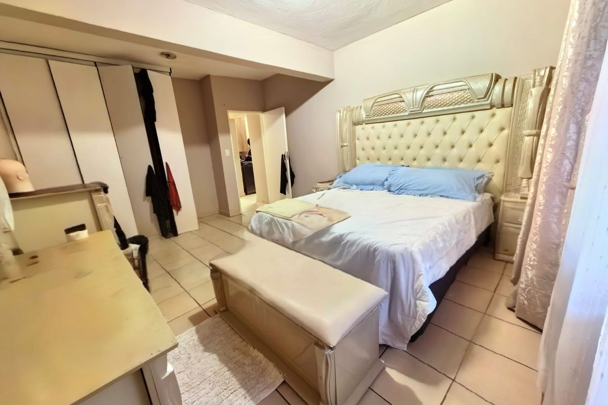 A bedroom featuring tiled flooring and a built-in wardrobe, offering a functional space with potential for cosmetic updates.