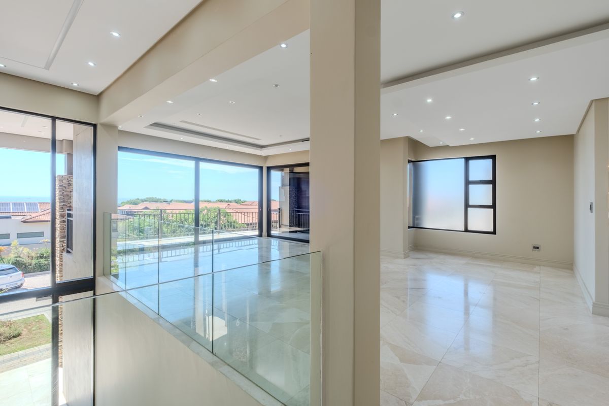 Spacious, modern open-plan living area featuring high-quality porcelain flooring, recessed lighting, and expansive glass sliding doors leading to a balcony with scenic views.