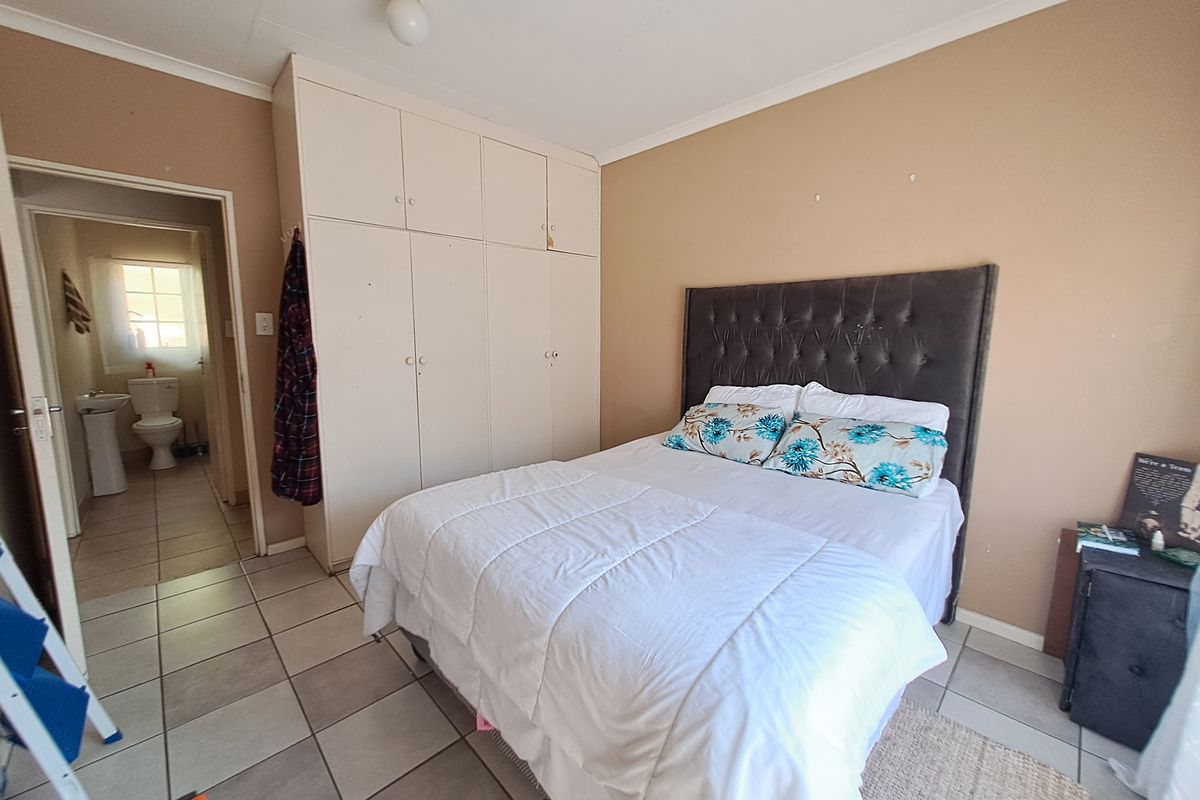 A bedroom featuring tiled flooring and built-in cupboards, with an adjoining bathroom visible through the doorway.