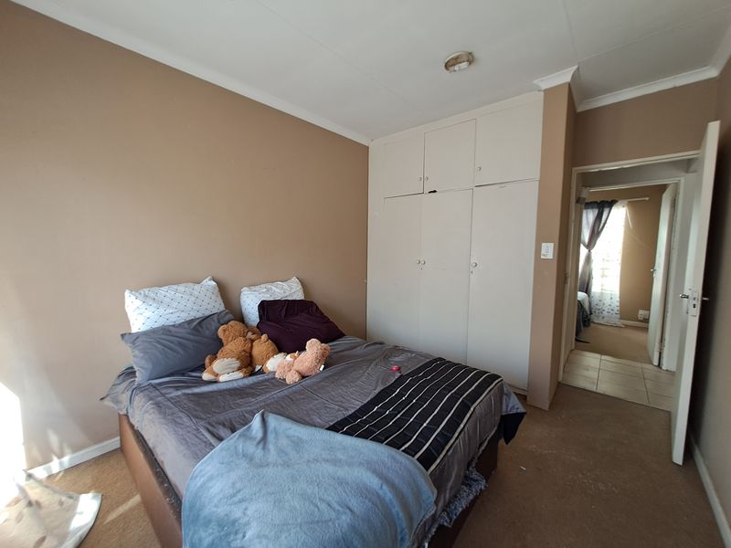 A bedroom featuring built-in cupboards and carpeted flooring, offering a functional space with potential for cosmetic updates.