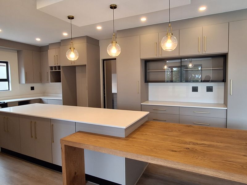 Modern kitchen featuring a large island with quartz countertops, integrated timber breakfast bar, gas stove, and ample built-in cabinetry with stylish pendant lighting.