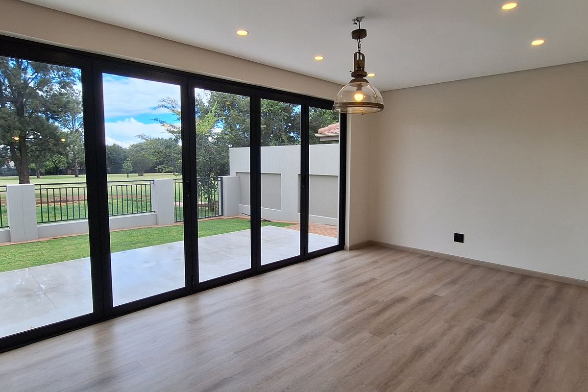 Bright and modern living area featuring large aluminium stacker doors that open onto a private garden patio, finished with high-quality laminate flooring.
