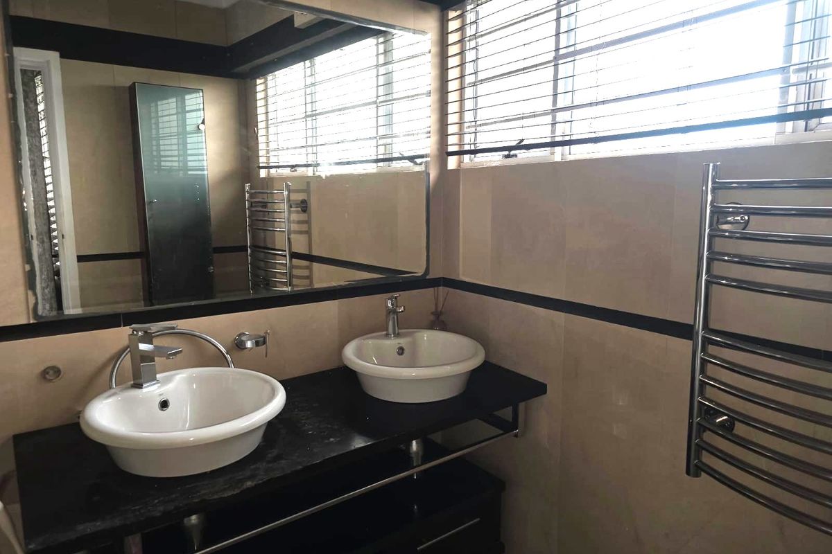 Modern bathroom featuring a double vanity with vessel sinks, large wall-mounted mirror, and a chrome heated towel rail.