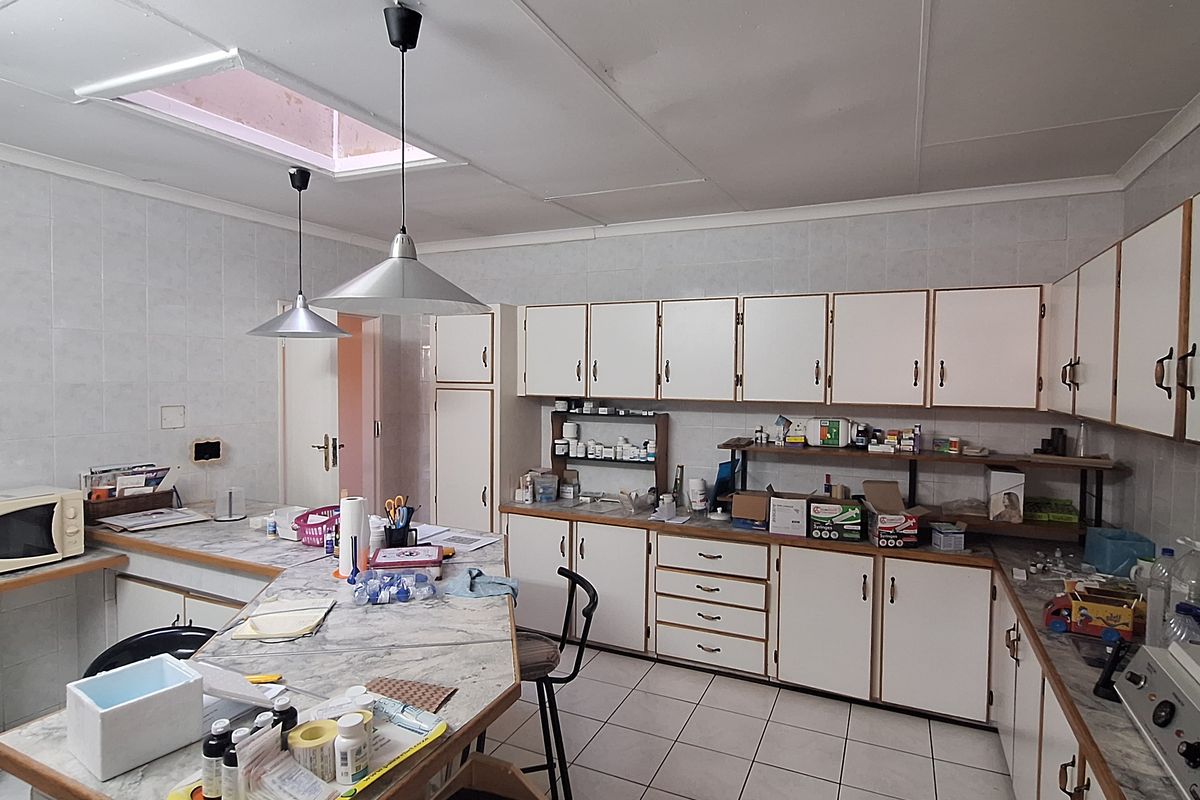 A functional kitchen featuring tiled countertops, ample cabinetry, and a central island with pendant lighting, offering a practical layout for daily meal preparation.