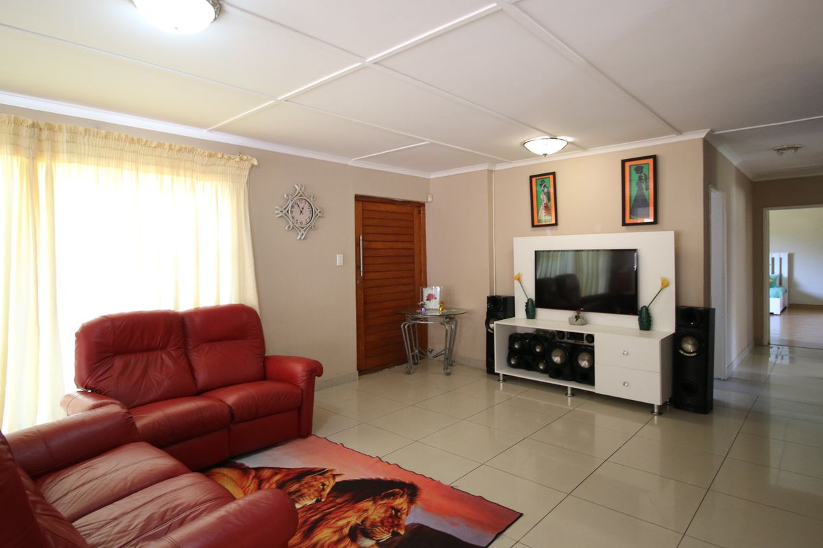A spacious living room featuring neutral wall tones, large format floor tiles, and a built-in media unit, offering a comfortable and functional family space.