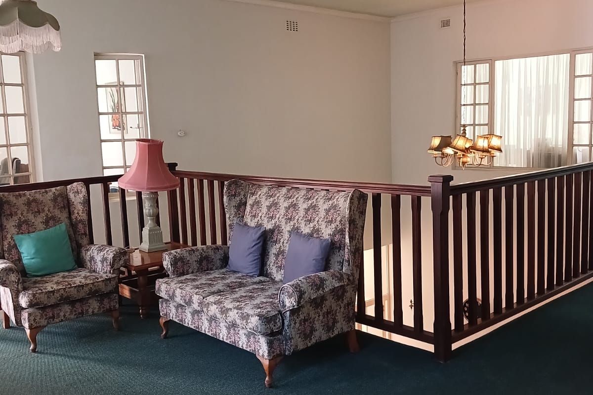 A spacious landing or living area featuring a traditional timber balustrade, multi-pane windows, and classic decorative pendant lighting fixtures.