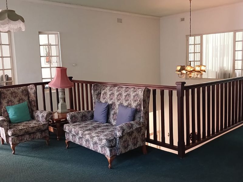 A spacious landing or living area featuring a traditional timber balustrade, multi-pane windows, and classic decorative pendant lighting fixtures.