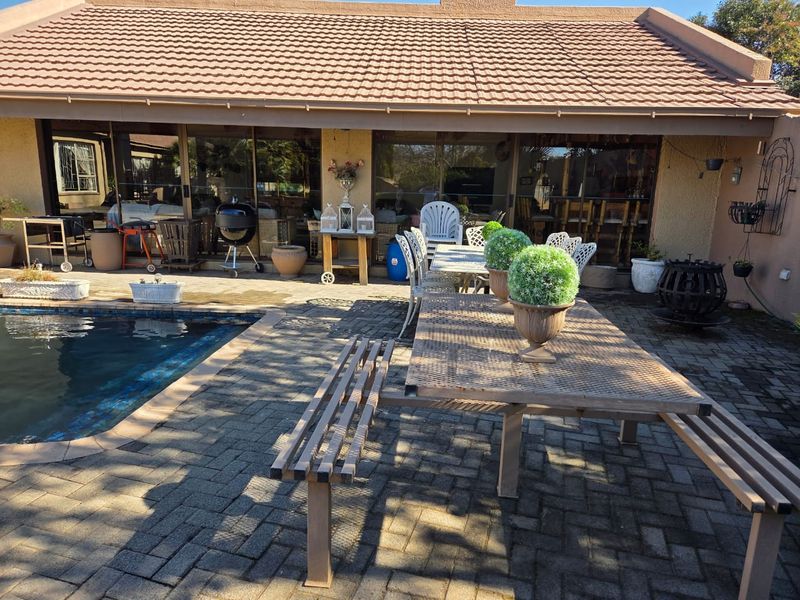 A spacious outdoor patio area featuring paved flooring, a swimming pool, and direct access to the home through large sliding glass doors.