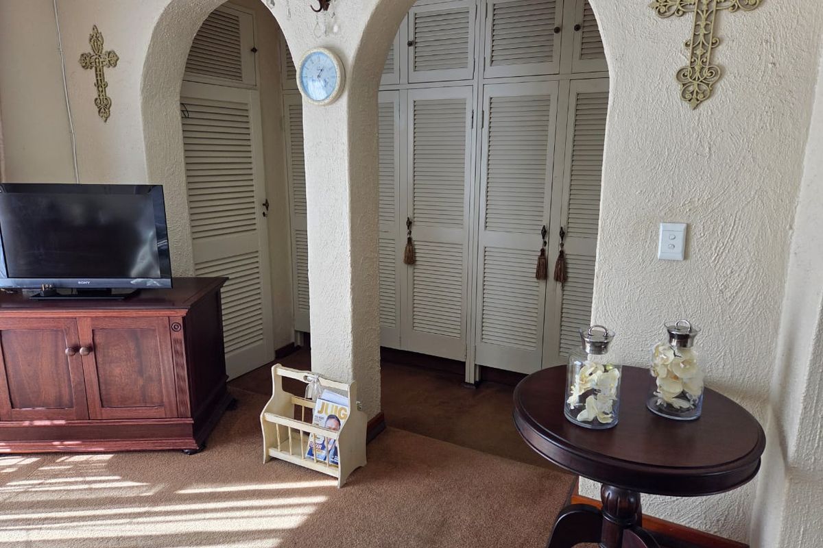 A living area featuring distinctive arched doorways leading to built-in louvered storage cupboards and textured wall finishes.