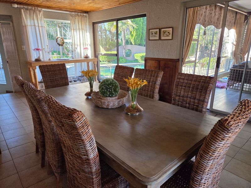 A dining room featuring tiled flooring, timber-clad ceiling, and large sliding glass doors providing natural light and views of the outdoor pool area.