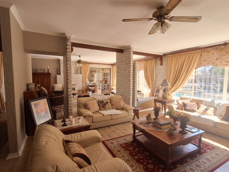 Spacious open-plan living area featuring exposed brick pillars, wood-look flooring, and a ceiling fan, creating a warm and inviting atmosphere.