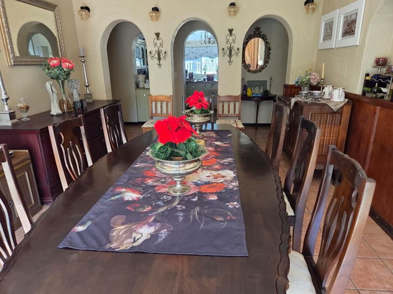 A formal dining room featuring distinctive arched doorways leading to adjacent living spaces, tiled flooring, and textured wall finishes.