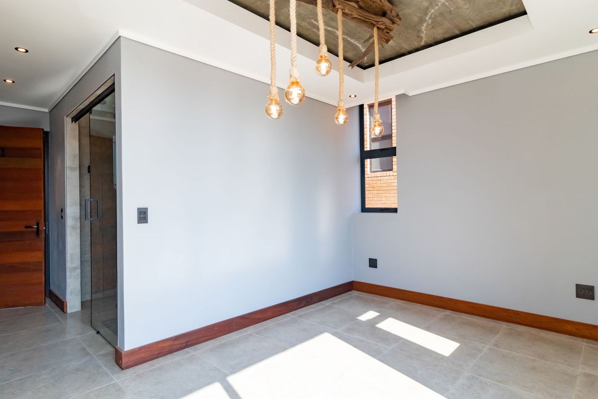 A bright, modern bedroom featuring tiled flooring, timber skirting, and a unique recessed ceiling with decorative pendant lighting.