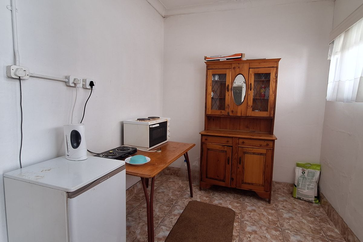 A compact kitchen area featuring basic tiled flooring, surface-mounted electrical outlets, and a small prep space.
