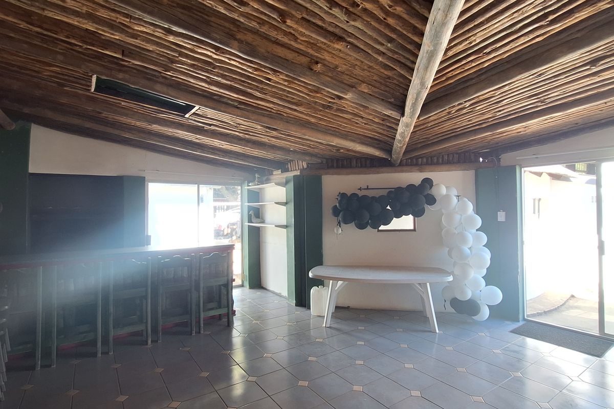 Spacious entertainment area featuring a unique exposed timber rafter ceiling, tiled flooring, and a built-in bar counter with sliding door access to the exterior.