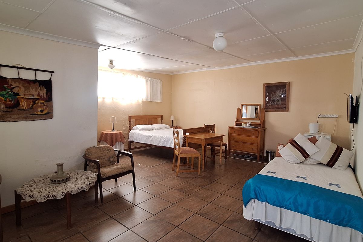A spacious bedroom featuring tiled flooring and a functional layout with multiple sleeping areas.