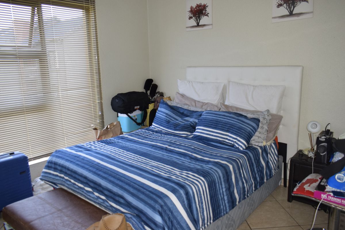 A functional bedroom featuring tiled flooring and venetian blinds, providing a neutral base for personalization.