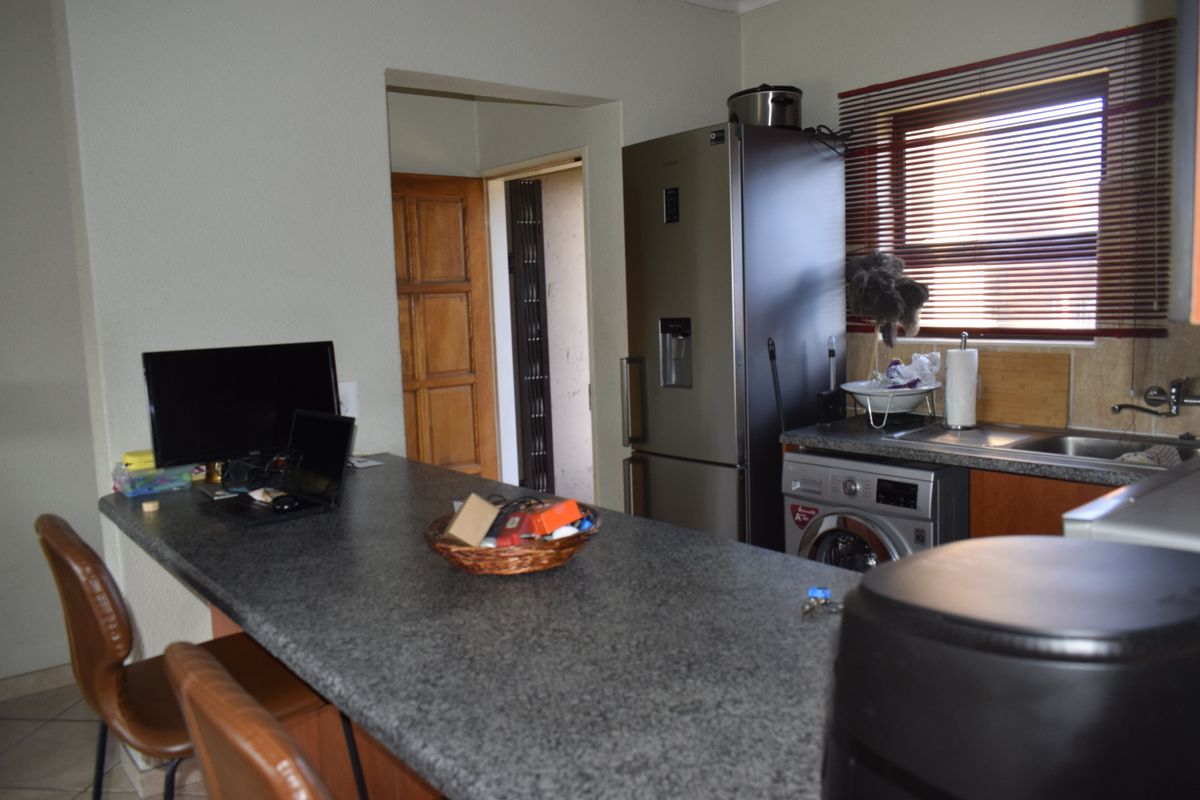 A functional kitchen area featuring a granite breakfast bar, built-in cabinetry, and a stainless steel sink with window blinds.