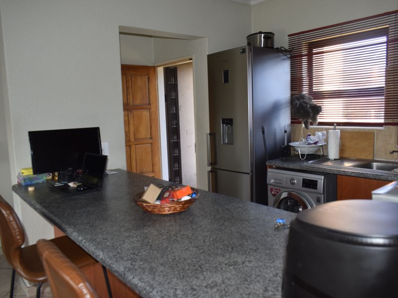 A functional kitchen area featuring a granite breakfast bar, built-in cabinetry, and a stainless steel sink with window blinds.