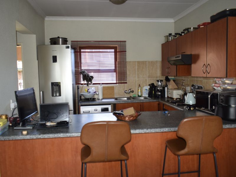 A functional kitchen featuring laminate cabinetry, a breakfast bar, and a tiled backsplash, providing a practical layout for daily meal preparation.