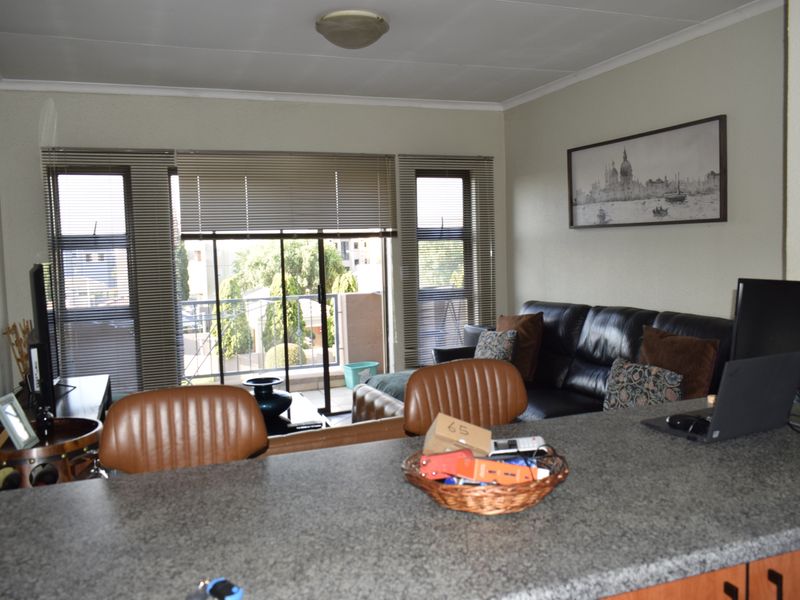 Open plan living area featuring a granite breakfast bar, sliding glass doors leading to a balcony, and neutral wall finishes.