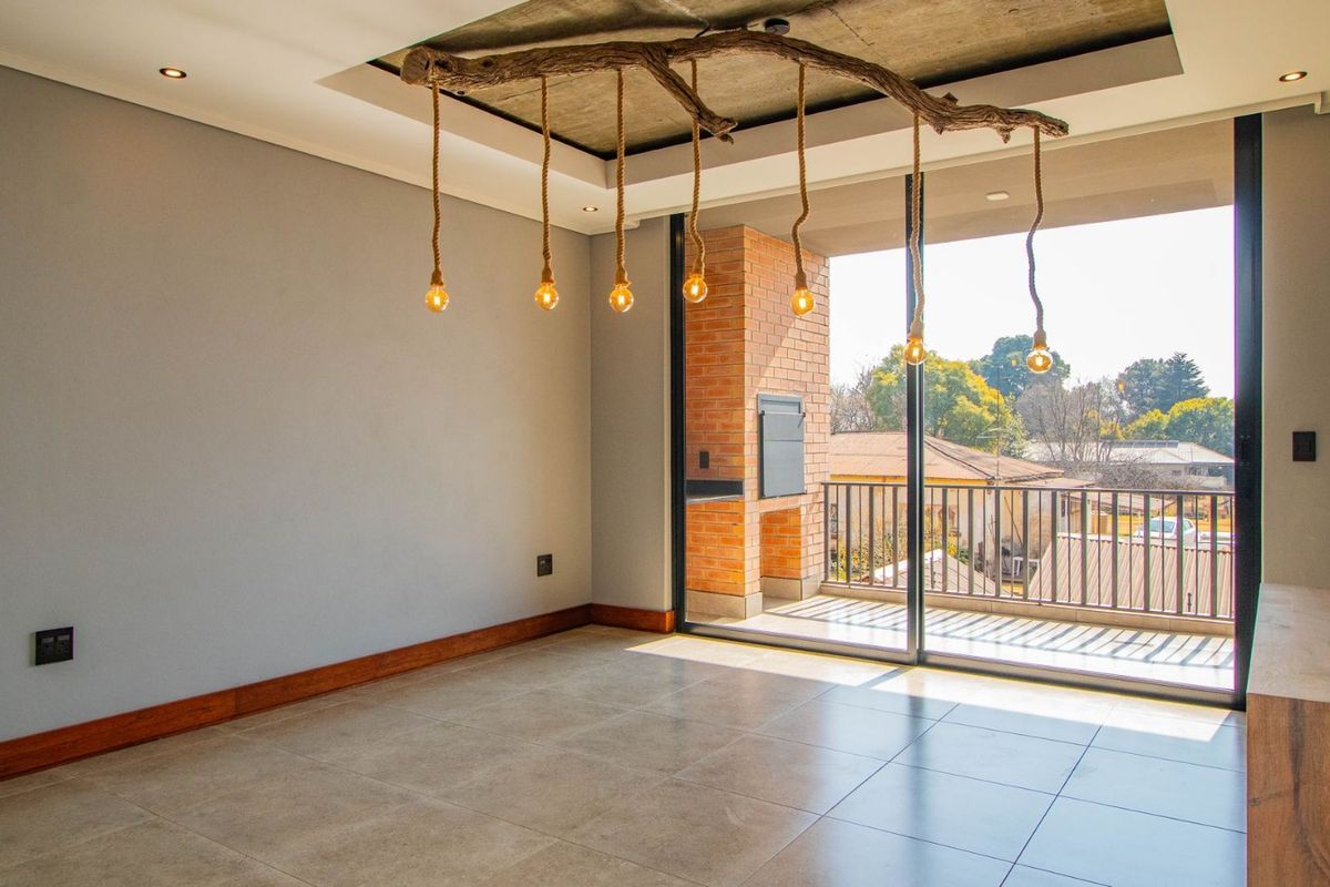 Spacious living area featuring tiled floors, a unique recessed ceiling with feature lighting, and large sliding doors opening onto a private balcony.