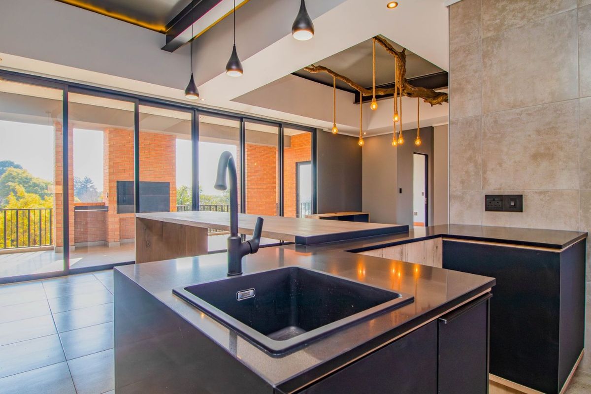 Modern open-plan kitchen featuring a sleek island with undermount sink, stone countertops, and large sliding doors leading to a spacious balcony.