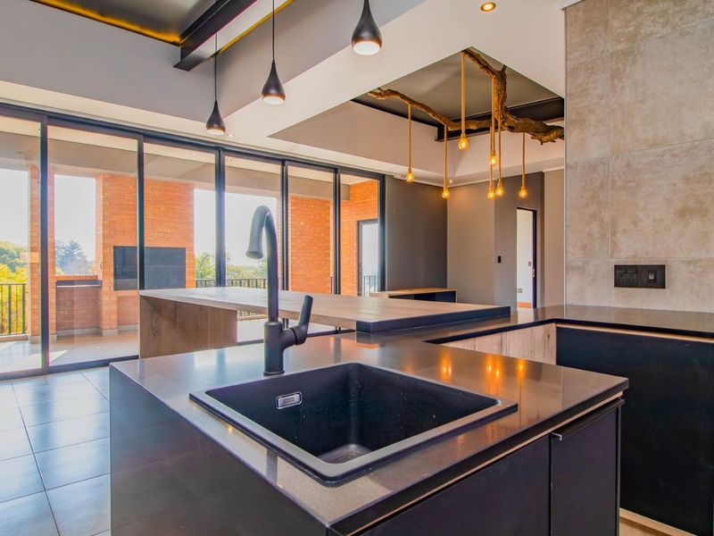 Modern open-plan kitchen featuring a sleek island with undermount sink, stone countertops, and large sliding doors leading to a spacious balcony.