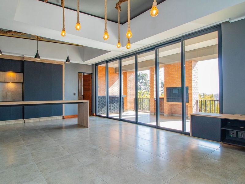 Spacious open-plan living area featuring modern built-in cabinetry, large format floor tiles, and expansive sliding glass doors leading to a covered balcony.