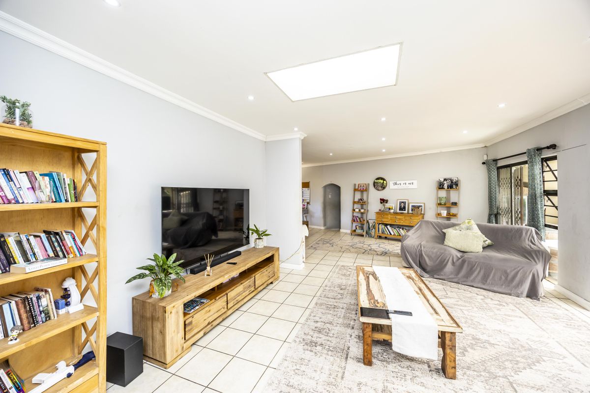 Spacious living area featuring tiled flooring, recessed ceiling lighting, and a large skylight, providing a bright and open atmosphere for relaxation.