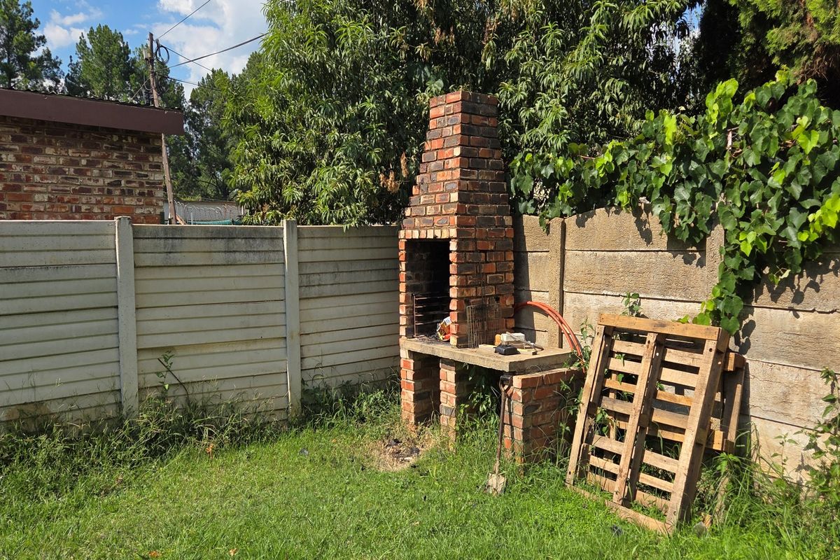 Rear garden area featuring a traditional brick built-in braai and precast concrete boundary walling, offering potential for outdoor entertainment space development.